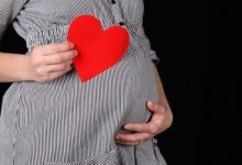 mulher grávida segurando um coração de papel