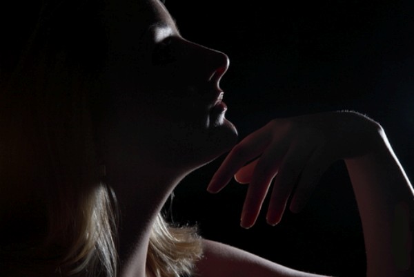 mulher no escuro com a mão no queixo